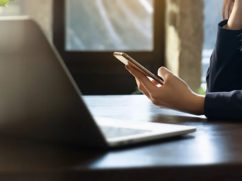 midsection-businesswoman-using-mobile-phone-table